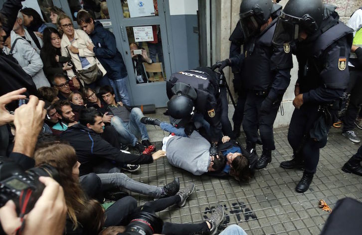 Policías desalojando a la gente en un colegio de Barcelona. (Pau BARRENA/AFP)