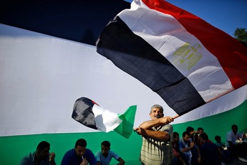 Un hombre ondea una bandera palestina en Gaza tras el acuerdo entre Hamas y Al-Fatah. (Mohammed ABED/AFP PHOTO)