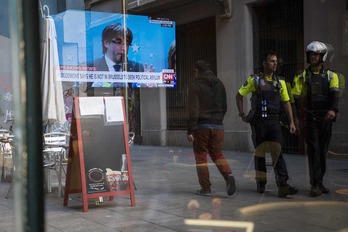 El reflejo en un bar de Barcelona de la emisión en directo de la comparecencia de Puigdemont de Bruselas. (Josep LAGO | AFP)