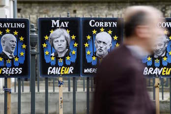 Carteles con los rostros de Theresa May y Jeremy Corbyn. (Tolga AKMEN/AFP)