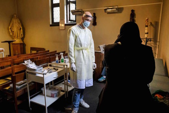 Un sanitario de Geneeskunde voor het Volk (Medicina para el Pueblo) atiende a una mujer en Amberes. (Dirk WAEM/AFP)