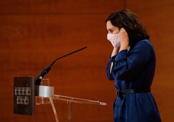 La presidenta madrileña se coloca la mascarilla antes de valorar el fallo. (AFP)