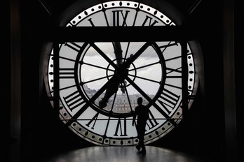 Un solitario visitante pasa ante el reloj del museo de Orsay, mientras el Gobierno baraja limitar horarios por la Covid-19. (Ludovic MARIN / AFP)