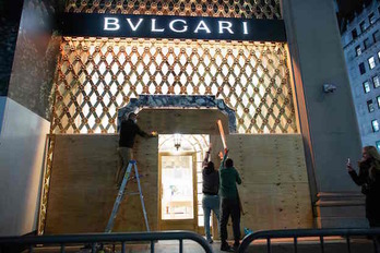 Operarios protegen con maderas la entrada de una tienda de la firma de lujo Bulgari en Nueva York. (KENA BETANCUR / AFP)