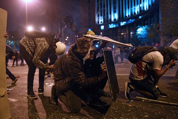 Manifestantes a favor de Vizcarra se protegen de las cargas de la Policía en Lima. (Ernesto BENAVIDES/AFP)