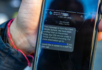 Una madre muestra el mensaje de texto que ha recibido explicando que la escuela de su hijo, en Chelsea (Massachusetts), está bajo amenaza de un tiroteo este 17 de diciembre. (Joseph PREZIOSO/AFP)