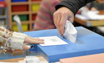 Un votante deposita su papeleta en una urna. 