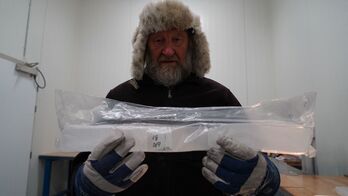 El investigador  Jørgen Peder Steffensen sostiene parte de una muestra de hielo.