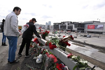 Dos ciudadanos depositan flores frente a la sala donde se produjo el ataque.