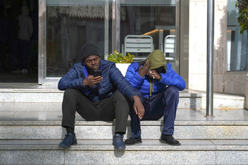 Dos jóvenes migrantes con sus teléfonos móviles en Málaga.