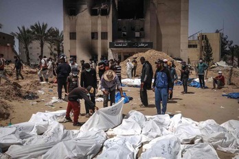  Trabajadores de Defensa Civil, con los cuerpos exhumados en las fosas del hospital Nasser.