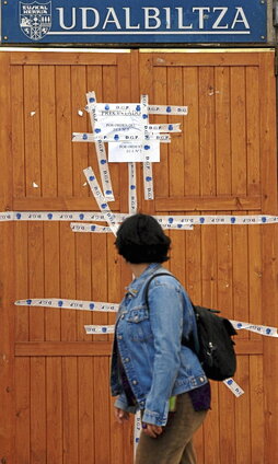 Una mujer pasa  ante la puerta precintada de la sede de Udalbiltza de Gasteiz.