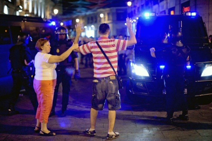 Un hombre levanta sus brazos frente a una dotación policial en Madrid. (Pedro ARMESTRE/AFP)