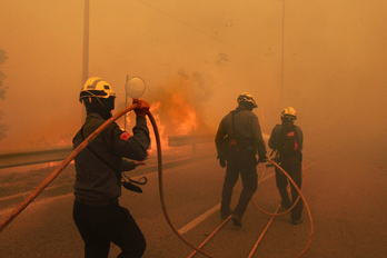 Bomberos tratan de sofocar las llamas en plena carretera. (AFP/Joan CASTRO)
