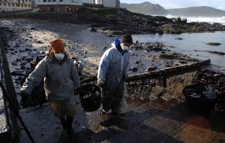 Voluntarios trabajan en la limpieza de la playa de Muxia en una foto de archivo tomada el 23 de noviembre de 2002. (Christophe SIMON/AFP)