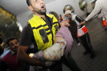 Un trabajador de los servicios de rescate lleva el cuerpo de una niña al hospital. (Mohammed ABED / AFP)