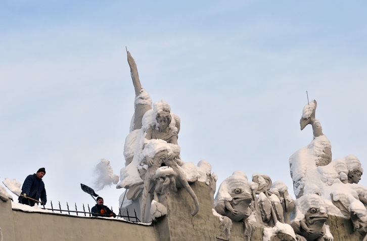 Langile batzuk elurra kentzen eraikin bateko eskulturetatik, Kiev hiriburuan. (Sergei SUPINSKY/AFP) 