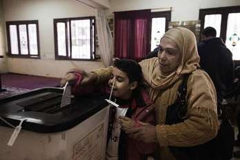 Una mujer deposita su voto junto a su hijo en el referéndum sobre la nueva Constitución. (Gianluigi GUERCIA/AFP)