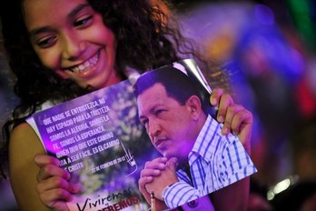 Una joven sostiene el retrato de Hugo Chávez. (Héctor RETAMAL/AFP) 
