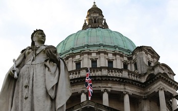 Imagen de la estatua de la reina Victoria con la bandera británica al fondo ondeando en el Ayuntamiento de Belfast. (Peter MUHLY/AFP)