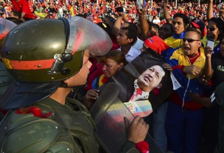 Un militar custodia el féretro de Chávez ante la marea que abarrotó las calles de Caracas. (Luis ACOSTA/AFP)
