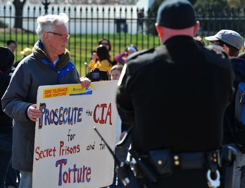 Un hombre muestra un cartel en el que acusa a la CIA de torturar a prisioneros iraquíes, durante las protestas ante la Casa Blanca por el décimo aniversario de la invasión. (Mladen ANTONOV/AFP)