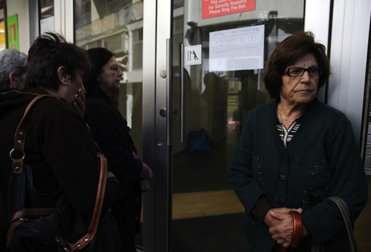 Ciudadanos chipriotas aguardan a las puertas de una sucursal bancaria. (Yiannis KOURTOGLOU/AFP PHOTO)