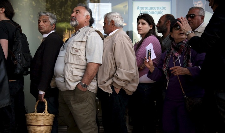 Personas aguardan su turno a las puertas de su entidad bancaria. (Ylannis KORTOGLOU / AFP)