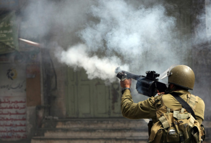 Un miembro de las fuerzas de Israel dispara gases lacrimógenos en Hebron. (Hazen BADER/AFP)