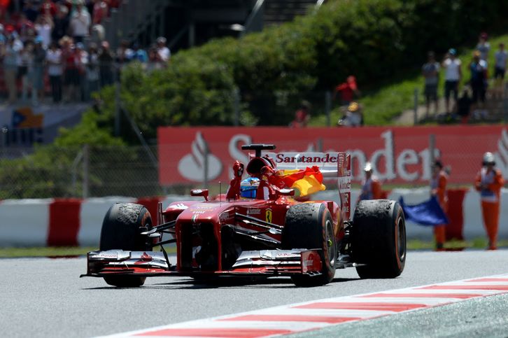 Alonso celebra la victoria con la bandera española. (Lluis GENE / AFP)