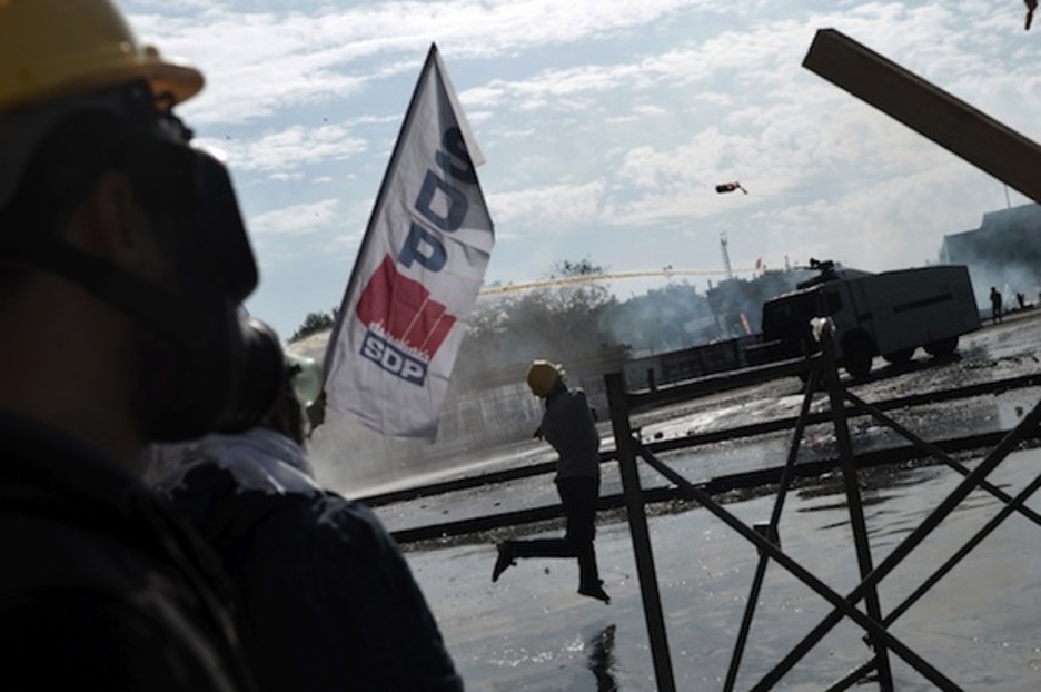 Manifestantes lanzan objetos contra los blindados de la Policía. (Aris MESSINIS/AFP PHOTO)