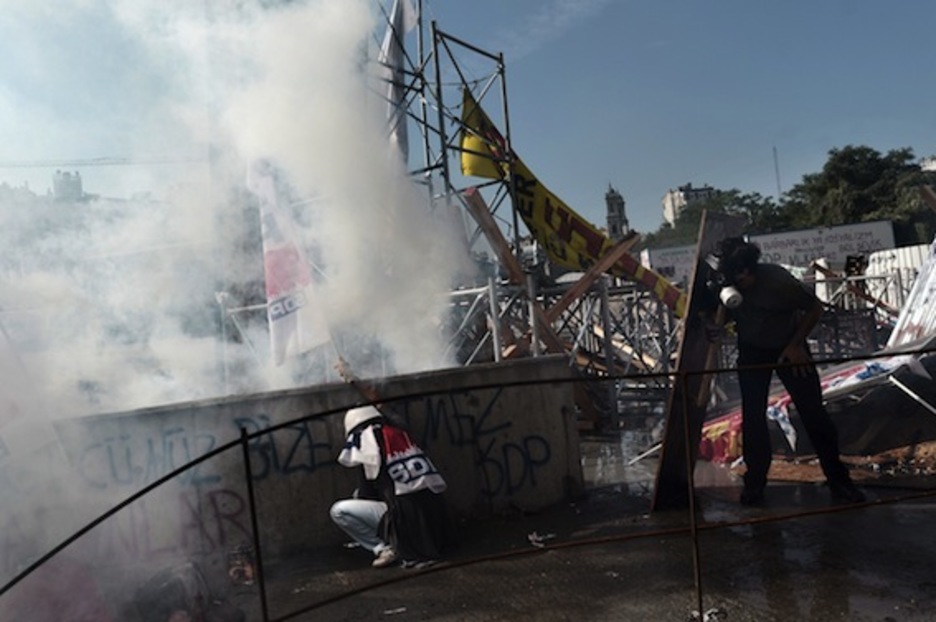 Dos manifestantes se protegen de la Policía tras las barricadas. (Aris MESSINIS/AFP PHOTO)