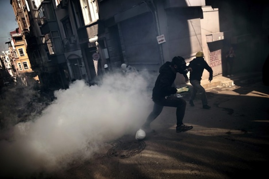 Dos manifestantes corren a resguardarse de los gases lacrimógenos. (Aris MESSINIS/AFP PHOTO)