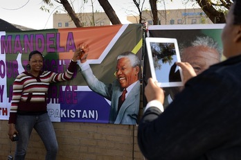 Una mujer se toma una foto a las afueras del hospital donde permanece ingresado Nelson Mandela. (Eric FEFERBERG/AFP PHOTO)