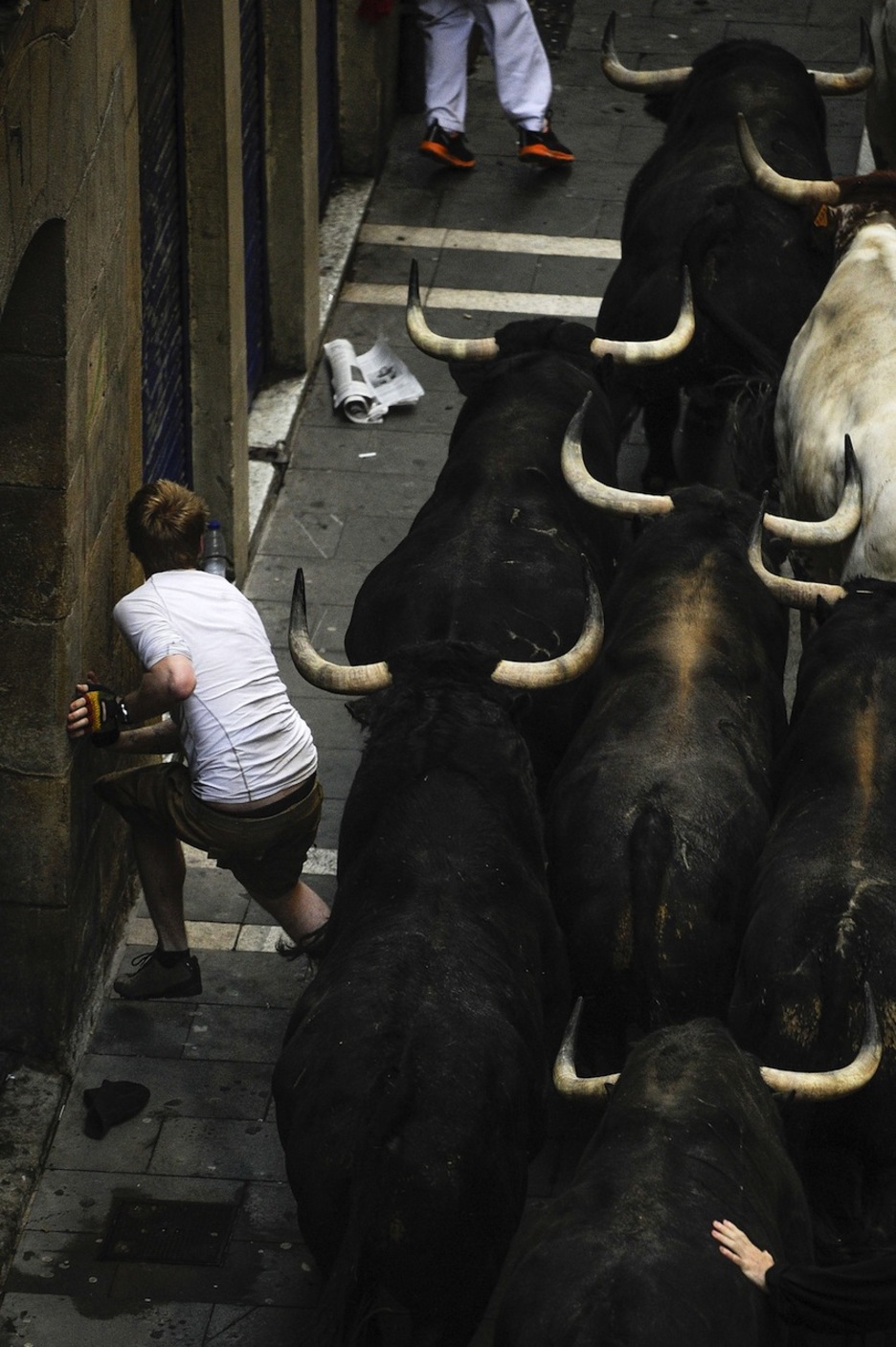 Un corredor se pega a la pared a pocos centímetros de la manada. (Pedro ARMESTRE/AFP)