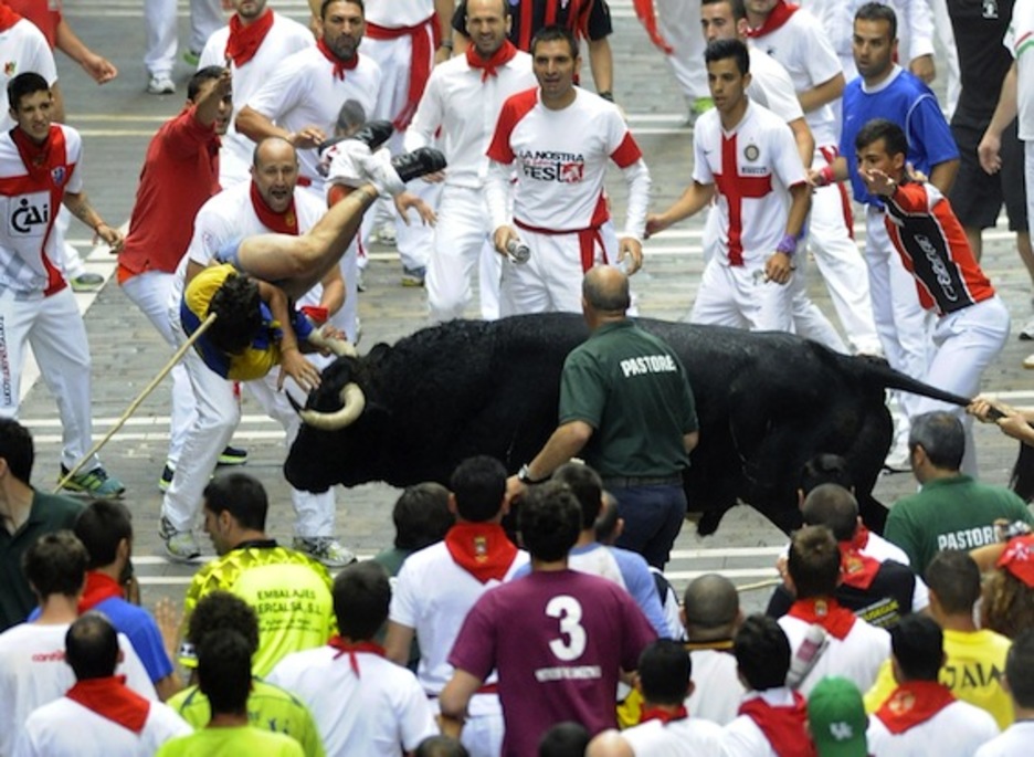Un toro zarandea al joven al que ha empitonado en Estafeta. (Ander GILLENEA/AFP PHOTO)