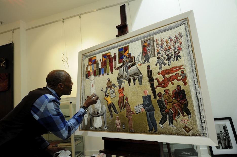 El artista Alfred Toba da los últimos retoques a su cuadro para una exposición con motivo del aniversario de Mandela (Alexander JOE / AFP)