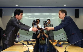 Los representantes de las dos Coreas estrechan sus manos tras el acuerdo para reabrir Kaesong. (AFP PHOTO)