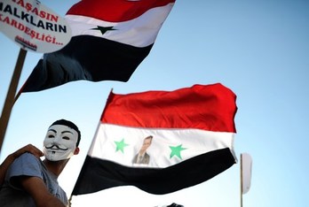 Un manifestante porta la bandera siria con la foto de Al-Assad durante una protesta contra la posible intervención militar de EEUU sobre el territorio. (Bulent KILIC/AFP)