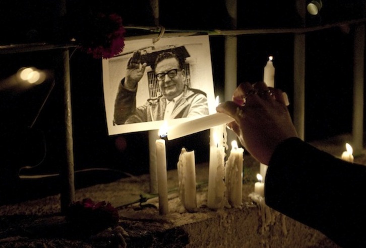 Una mujer enciende una vela junto a una fotografía de Salvador Allende, en las inmediaciones del Estadio Nacional. (Claudio SANTANA/AFP PHOTO)