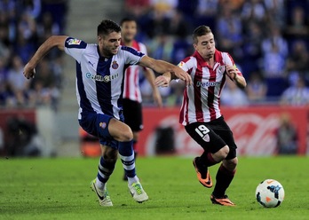 Iker Muniain trata de zafarse de la marca de David López. (Josep LAGO / AFP PHOTO)