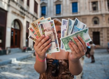 Una mujer muestra billetes de pesos CUP (mano izquierda) y pesos convertibles. (Yamil LAGE/AFP) 