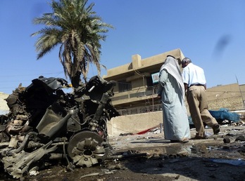 Dos iraquíes observan los daños provocados por un atentado en Bagdad. (Sabah ARAR/AFP PHOTO)