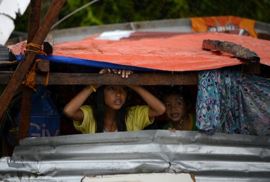 Dos niños observan desde una chabola los efectos del tifón. (Noel CELIS/AFP PHOTO)