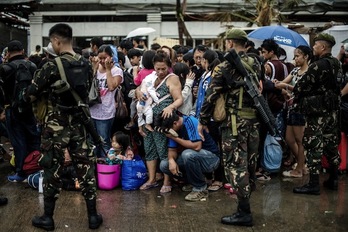 Tifoiak kaltetutako herritarrak, laguntza jasotzeko zain, soldaduen begiradapean. (Philippe LOPEZ/AFP PHOTO)