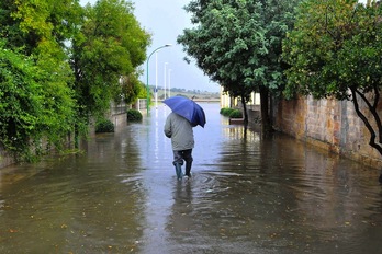 Un hombre camina por una calle totalmente inundada por el ciclón Cleopatra. (Angelo CUCCA/AFP)