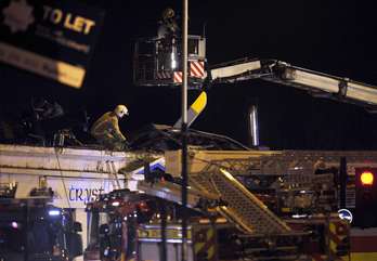 Servicios de rescate trabajan en el tejado del pub en le que se ha estrellado el helicóptero. (Andy BUCHANAN / AFP)