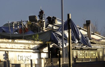 Servicios de emergencia trabajan en el techo del pub contra el que se estrelló el helicóptero. (Andy BUCHANAN / AFP)