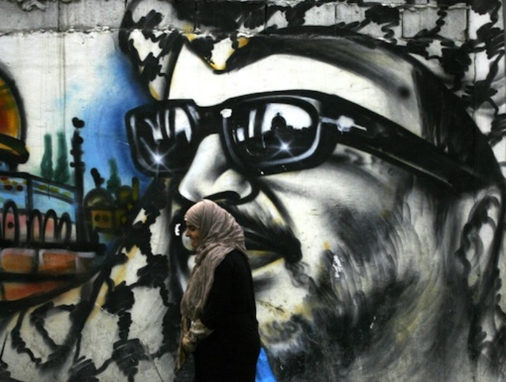 Una mujer camina ante un mural de Arafat en un campo de refugiados palestinos en Líbano. (AFP)