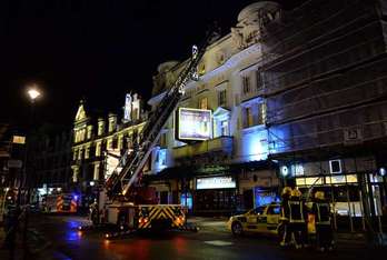 Los bomberos en el exterior del teatro, donde se ha desplomado parte del techo. (Leon NEAL/AFP)